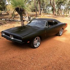 a black muscle car parked in the dirt