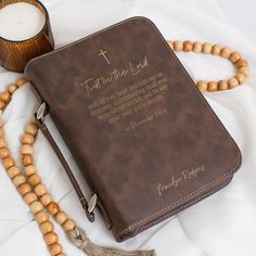 a brown bible with beads and a candle