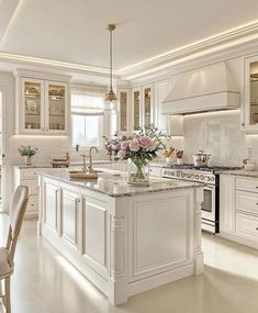 a large kitchen with white cabinets and an island in the middle is lit by lights