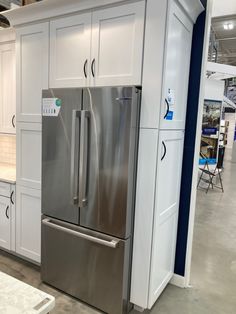 a stainless steel refrigerator and freezer combo in a showroom with white cabinetry