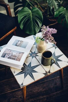 a table with a vase and some flowers on top of it next to a book