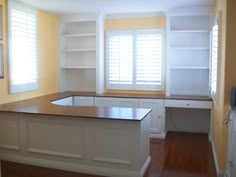 an empty kitchen with wooden flooring and white cabinets in the corner, along with open shelves