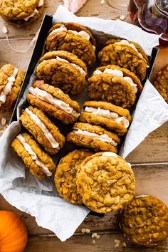 a box filled with cookies and frosting on top of a wooden table next to pumpkins