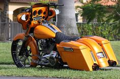 an orange motorcycle parked next to a tree