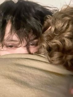 two people are wrapped up in blankets and one person is looking at the camera with his eyes closed