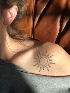 a woman with a sun tattoo on her shoulder