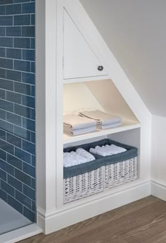 an attic bathroom with blue tile and white storage bins for towels, linens and blankets