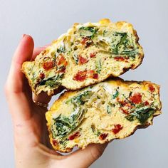 two pieces of bread with spinach and cheese on top are being held up by someone's hand