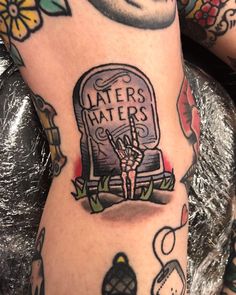 a tattoo on the leg of a person with tattoos and flowers around her legs, holding a sign that says laters waters