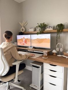 a woman sitting at a desk with two computer screens