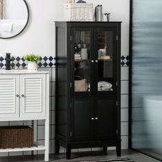 a bathroom with black and white tiles on the floor, a cabinet in the corner and a mirror above it