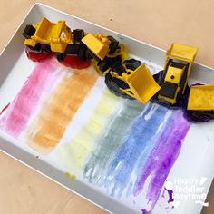 a tray that has some toys on it and is painted with watercolors to look like construction vehicles