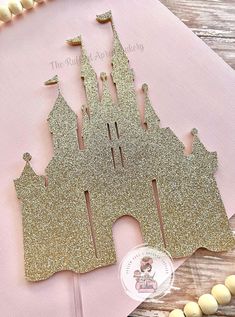 a gold glitter castle cutout on top of a pink napkin next to some candy