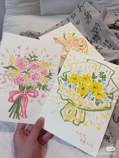 two handmade cards with flowers on them are being held in front of the camera