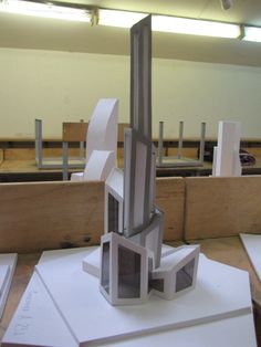 a sculpture is sitting on top of white paper and some other pieces are in the background