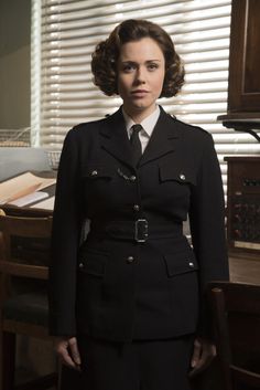 a woman in uniform standing next to a desk