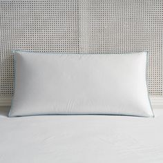 a white pillow on top of a bed next to a headboard with wicker walls behind it