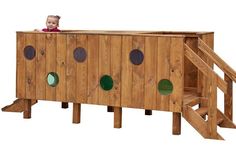 a toddler sitting on top of a wooden play structure with green circles around it