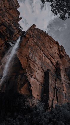 an image of a waterfall coming out of the side of a rock face with trees around it