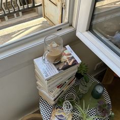 a stack of books sitting on top of a table next to a window sill