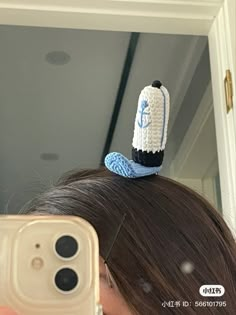 a woman taking a selfie in front of a mirror with a crocheted hat on top of her head