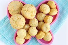 a pink heart shaped bowl filled with cookies on top of a blue towel next to a pair of scissors