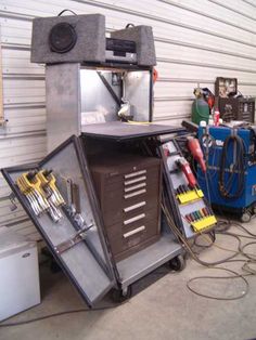 a garage area with tools and equipment on the floor, including an open tool cabinet