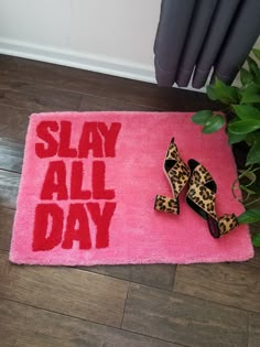 two pairs of shoes sitting on top of a pink rug that says slay all day