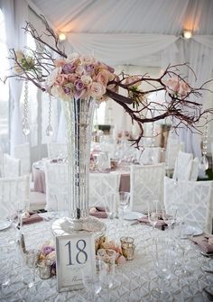 the table is set for an elegant wedding with flowers and candles in vases on it