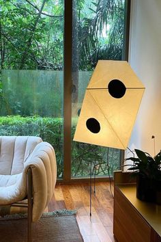 a living room with a couch, table lamp and large window looking out onto the woods