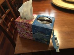 a tissue dispenser sitting on top of a wooden table