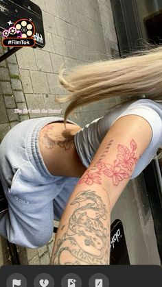 a woman with long blonde hair and tattoos on her arm