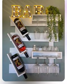 there is a wine bottle and two glasses on the shelf next to the bar sign