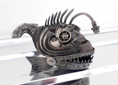 a metal fish sculpture sitting on top of a glass shelf