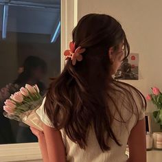 a girl with flowers in her hair looking out the window at another person standing nearby