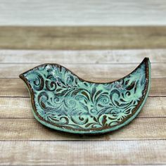 a green bird shaped dish sitting on top of a wooden table