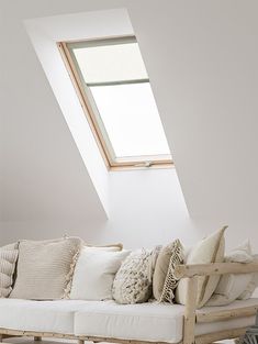 a white couch sitting under a skylight in a living room