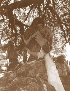 an old photo of two people hugging under a tree