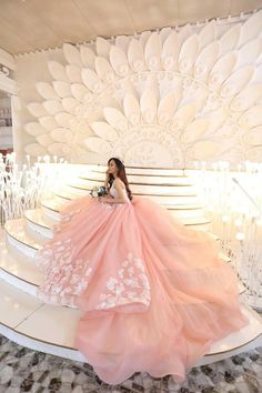 a woman in a pink dress sitting on some stairs