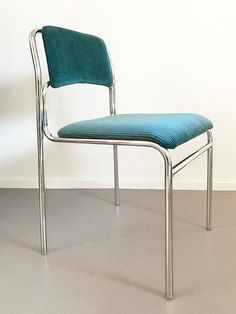 a blue chair sitting on top of a floor next to a white wall in an empty room