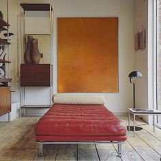 a red couch sitting in front of a painting on the wall