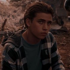 a young man sitting on the ground in front of a motorcycle and looking at the camera