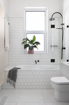 a bathroom with white tile and black accents