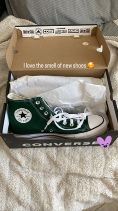 a pair of green converse shoes in a box on a bed with the words i love the smell of new shoes