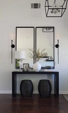 a black table with two mirrors on it and some lights hanging from the ceiling above