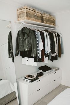 an organized closet with clothes and shoes hanging on the rack, next to a bed