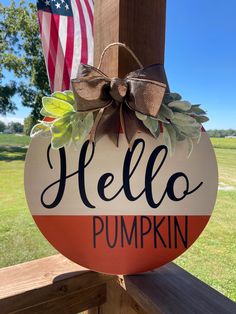 a sign that says hello pumpkin with an american flag in the background