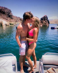 a man and woman kissing on the back of a boat