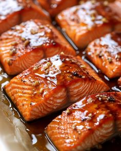 some salmon fillets are being cooked in brown sauce