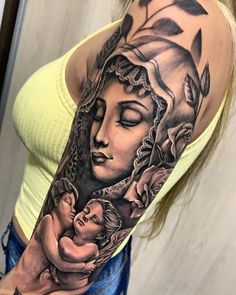 a woman with a tattoo on her arm is holding a baby in her arms and she has